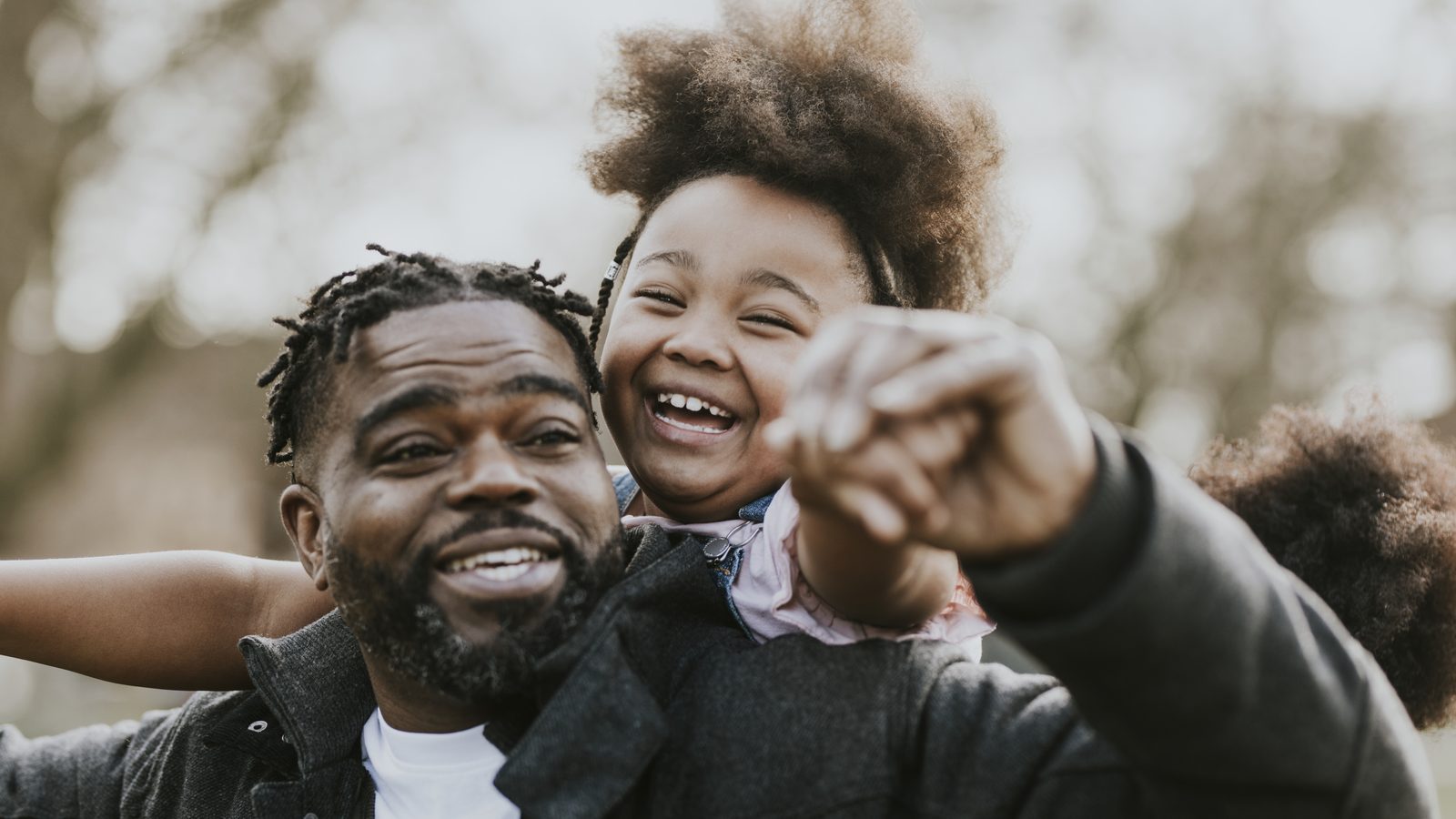 A father and his daughter outdoors, her arm around him, pointing at something ahead